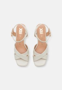 Sandalias de tiras beige con diseño entrecruzado, punta cuadrada y correa en el tobillo. Material ligeramente texturizado con una plantilla suave. Interior con marca.