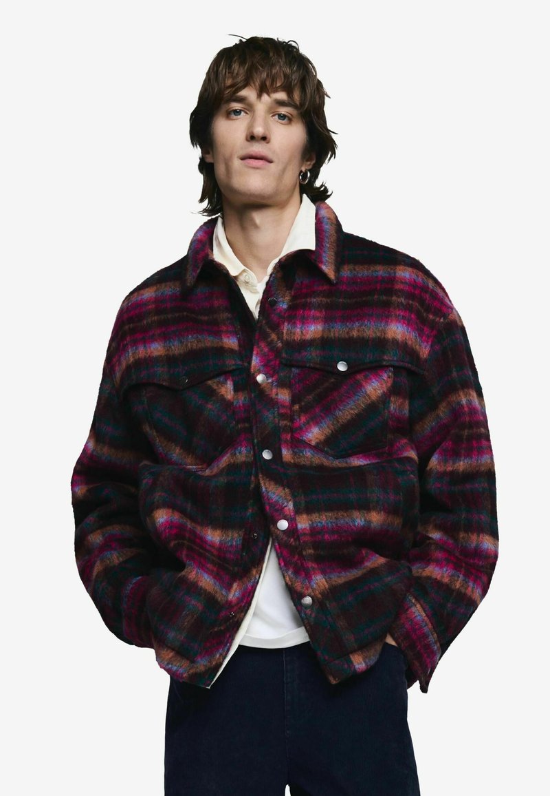 Ruuduline jakk lillakas, pruunis ja türkiissinis toonides. Omab ees nööbitavat sulgemist, kahte rinnataskut ja kraet. Valmistatud tekstuurse kangaga.