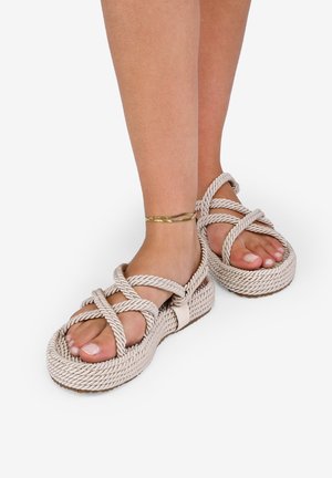 Sandalias de cuerda entrecruzadas en beige, con un diseño tejido y texturizado y una suela gruesa, que cuentan con una correa ajustable para un mejor ajuste.