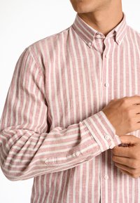 Camicia button-down a righe rosa chiaro e bianco con colletto classico e dettagli sui polsini, realizzata in un tessuto texture.