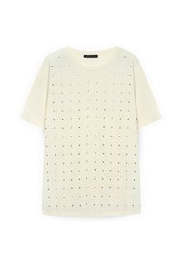 Camiseta corta de manga hecha de una tela suave, de color crema, que presenta un patrón de cuadrícula con pequeños cuadrados negros y acentos circulares distribuidos de manera uniforme.