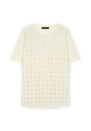 Tricou crem cu mânecă scurtă, realizat dintr-un material moale, având un model cu o rețea de mici accente pătrate și circulare negre distribuite uniform.