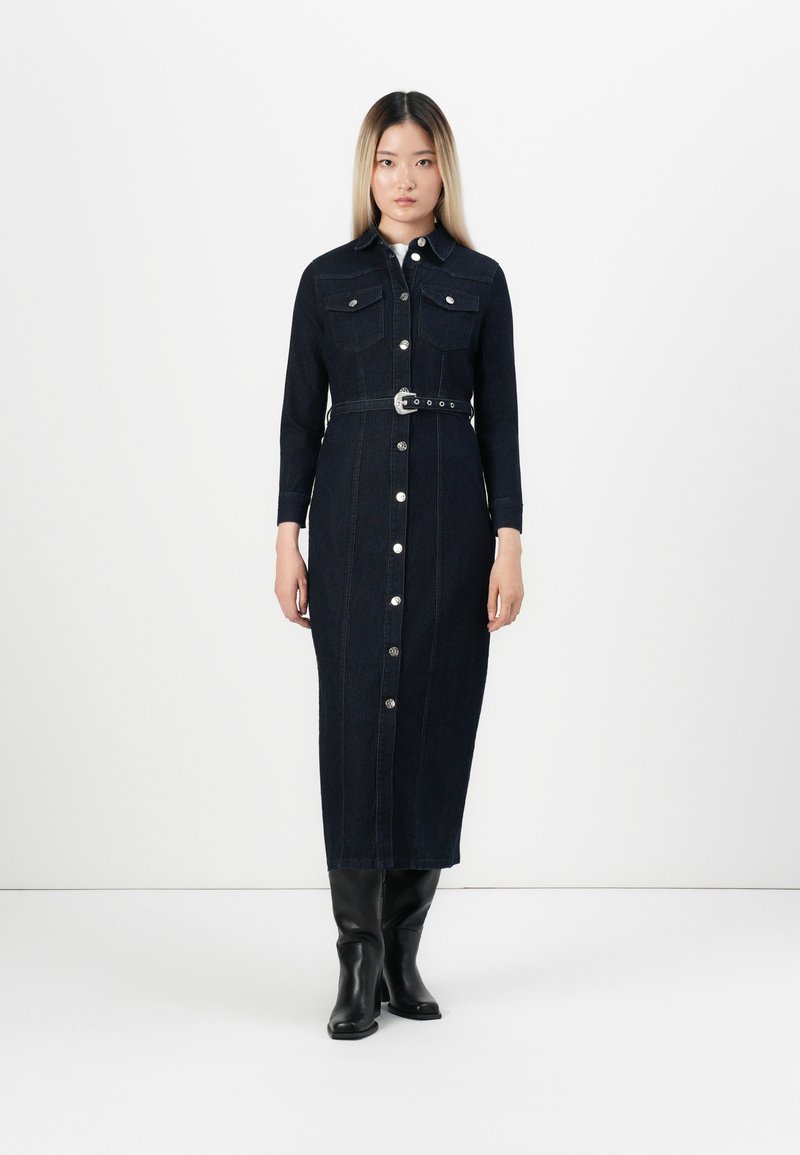 Robe chemise en denim bleu marine, avec des manches longues, deux poches poitrine, des boutons sur le devant, une taille ceinturée et une coupe droite.