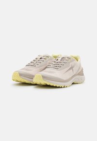 Jasno beżowe sneakersy z teksturowanymi powierzchniami, żółtymi akcentami i wzorzystymi sznurowadłami. Posiadają amortyzowaną podeszwę oraz oddychający materiał.