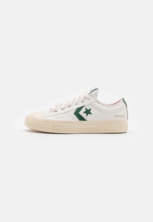 Sneakers in pelle bianca con accentuazioni in verde per la stella e il logo, lacci rosa chiaro, suola in gomma testurizzata e design classico a basso profilo.