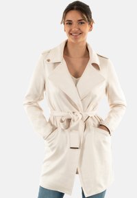 Cappotto trench crema con vita cintata, rever a punta e tasche laterali. Tessuto liscio con vestibilità su misura e silhouette moderna.