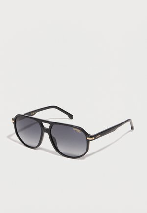 Black aviator-style sunglasses with dark gradient lenses and subtle gold accents on the frame, displayed on a light surface.