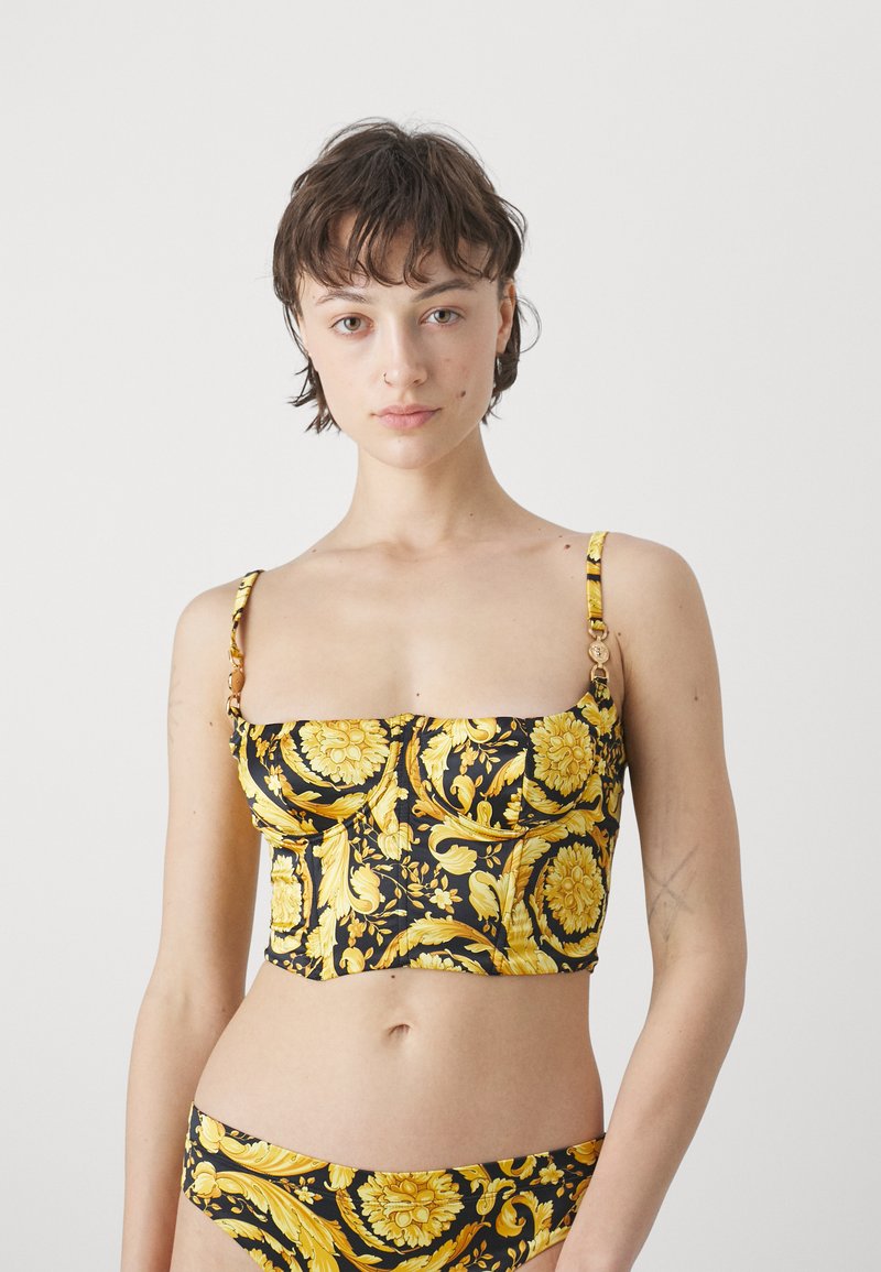 Μαύρο και κίτρινο λουλουδάτο cropped τοπ με λεπτές τιράντες, που διαθέτει χρυσές γυαλιστερές λεπτομέρειες και εφαρμοστή γραμμή. Απαλή υφή υφάσματος.