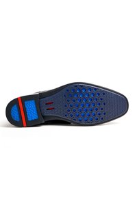 Semelle extérieure de chaussure avec une base noire, un motif hexagonal bleu, des accents rouges et une surface antidérapante texturée pour une meilleure traction.