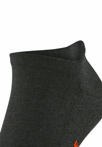 Schwarze Socke mit strukturiertem Strickdesign, ausgestattet mit einem niedrigen Knöchelschnitt und einem orangefarbenen Akzent an der Ferse. Weiches Material, flexibel und atmungsaktiv.