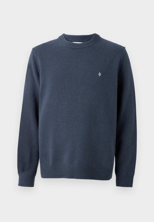 Pull à col rond bleu marine en tissu tricoté doux. Arborant des manches longues, des poignets côtelés et un petit logo brodé sur la poitrine.