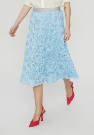 Lys blå blomsterlacemidi-nederdel med en sølvfarvet elastisk talje. Sammen med røde slingback-hæle, der har design med spidse tæer.