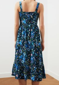 Blumendruckkleid in Marineblau, mit blauen und rosa Blumen, Spaghettiträgern, tailliertem Oberteil, ausgestelltem knielangen Rock und Rüsche am Saum.