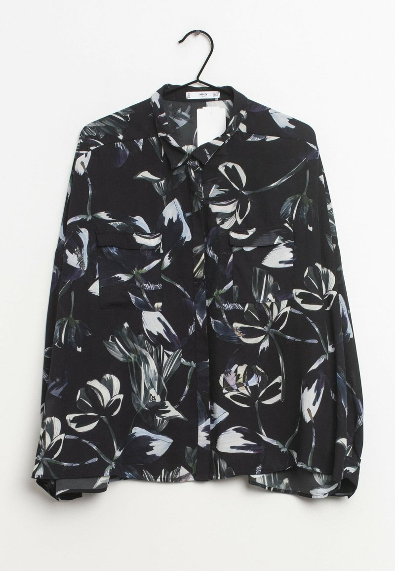 Camicia nera a maniche lunghe con un motivo floreale bianco e grigio, due tasche frontali sul petto, appesa a una gruccia nera.
