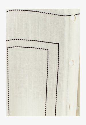 Bílá látka s černými tečkovanými stehy tvořícími obdélníky, vybavená knoflíkovým zapínáním. Měkká textura, lehká a mírně průsvitná.