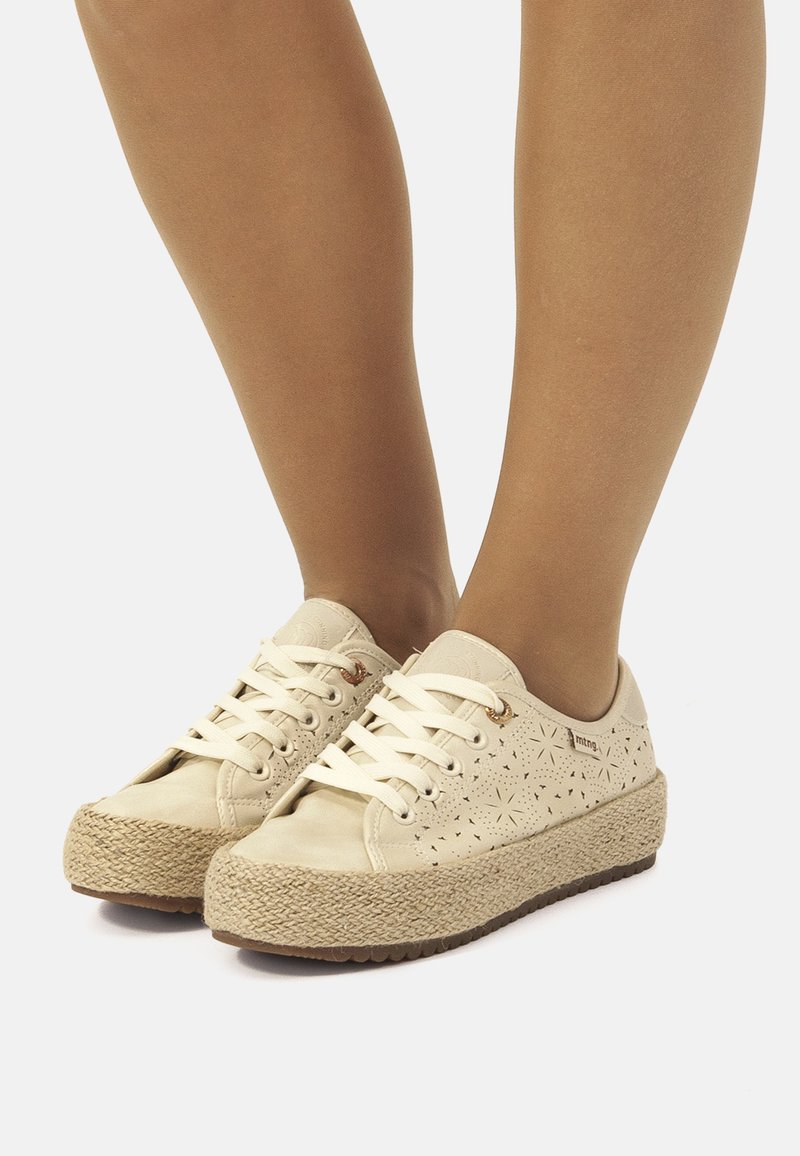 Baskets beiges avec un design perforé, semelle en espadrille tissée, fermeture à lacets et semelle en caoutchouc. Accentué par de petits trous décoratifs.