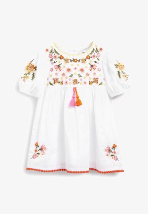 Bílá bavlněná šaty s barevným květinovým výšivkou, nafouknutými rukávy, kulatým výstřihem se žlutým lemem a oranžovými pom-pom detaily v pase.