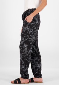 Schwarze Hose mit einem weißen, linearen botanischen Muster, ausgestattet mit einem elastischen Taillenbund mit Kordelzug, zwei seitlichen Taschen und einem lockeren Schnitt.