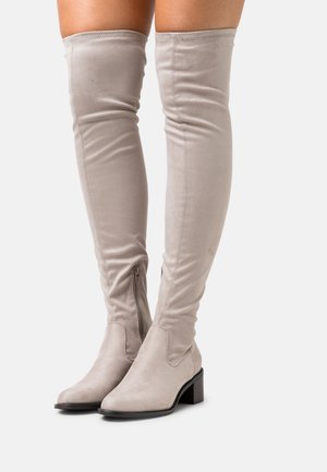 Bottes au-dessus du genou en suede gris clair avec un design ajusté, des fermetures éclair sur le côté et un talon bloc. Texture lisse avec semelles plates.