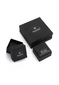 Schwarze Pappboxen in drei Größen, mit einem Logoetikett auf der Oberseite und einem Tag, der das verwendete Recyclingmaterial angibt.