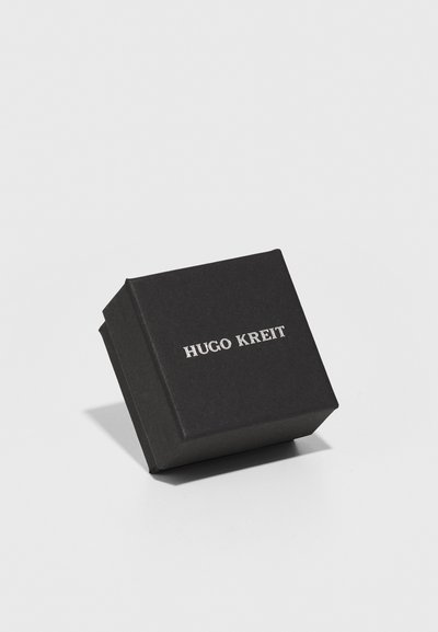 Crni kvadratni kutija s mat završnom obradom i srebrnim utisnutim logom "HUGO KREIT" na prednjoj strani, s oštrim kutovima i elegantnim dizajnom.