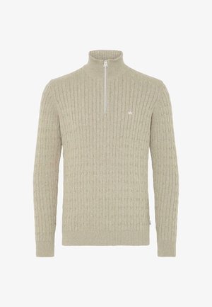 Bež särki, millel on kõrge krae ja veerandi lukuga, millel on ribakujundus ja väike tikandlogoga rinnal.