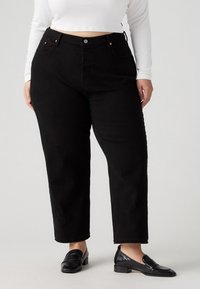 Black high-waisted jeans with a straight leg silhouette. Made from denim, featuring front pockets and brass hardware accents.