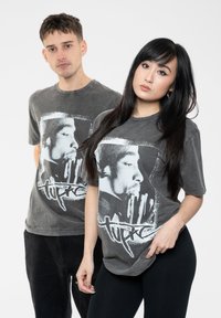 Gray cotton t-shirts featuring a graphic print of a man’s profile, with white accents and text resembling "Tupac." Relaxed fit, mid-length sleeves.