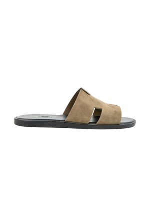 Brun ruskind slide sandal med udskåret design og sort flad sål vist fra siden på hvid baggrund.