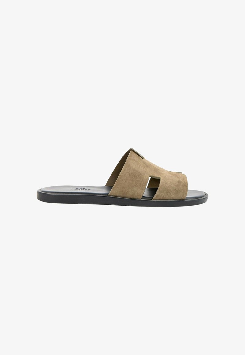 Sandale slide en daim marron avec design découpé et semelle plate noire vue de côté sur fond blanc.