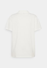 Short-sleeve polo shirt in off-white, featuring a classic collar, plain design, and soft cotton texture. No visible patterns or accents.
