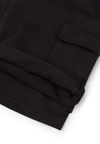Pantalons cargo noirs avec un revers, fabriqués en tissu léger, dotés d'une poche latérale et d'une surface lisse et texturée.