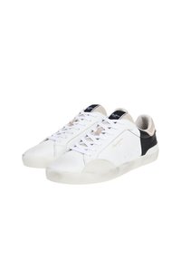 Sneakers in pelle bianca con accenti neri e beige, dotati di dettagli perforati, lacci piatti e suola in gomma texture.