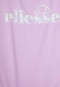Un tissu violet clair présente le logo "ellesse" en blanc avec un motif marbré multicolore. Texture lisse et design simple.