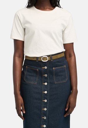 Personne portant une chemise blanche unie à manches courtes rentrée dans une jupe en jean bleu foncé avec boutons sur le devant, des poches et une ceinture marron.