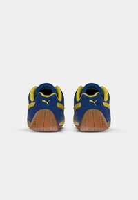 Blauwe en gele sport schoenen met een laag profiel, van suède materiaal, een gevoerde boord en een rubberen zool met een gestructureerd grip patroon.