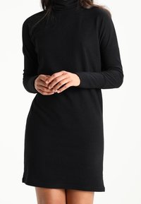 Robe longue à manches longues noire en col roulé, fabriquée en tissu doux avec une coupe décontractée, présentant un ourlet droit et un minimalisme dans les détails.