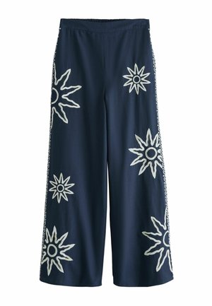Marineblauwe wijdbeens broek met witte zonnestraalborduursels aan de voorkant en zijkanten, elastische tailleband en decoratieve zijkantstiksels.