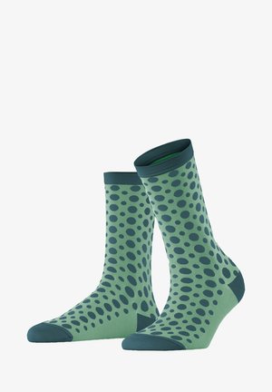 Chaussettes vertes avec des pois verts foncés, de longueur mi-mollet, poignet côtelé et pointe renforcée. Fabriquées en tissu lisse et extensible.
