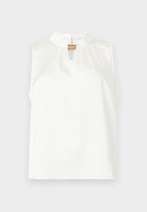 Blouse blanche sans manches avec col montant et petite ouverture devant, fermée par une seule agrafe décorative dorée.