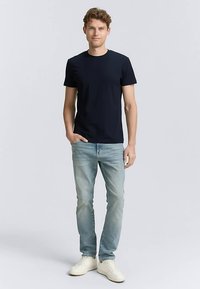 Mornarsko modra bombažna majica z okroglim izrezom, kratkimi rokavi, kombinirana s svetlomodrimi jeans hlačami in belimi supergami. Enostaven dizajn, priložnostna prileganost.