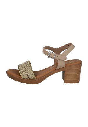 Sandalia de tacón beige con una correa dorada texturizada, hebilla ajustable en el tobillo y un tacón de bloque de madera. Diseño sutil con materiales transpirables.