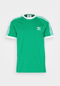 Grön bomull T-shirt med vita detaljer, korta raglanärmar och en liten vit Adidas-logotyp på bröstet. Tre vita ränder på ärmarna.