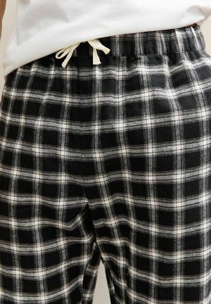 Black and white plaid pajama pants feature an elastic waistband with a drawstring and a soft, textured fabric.