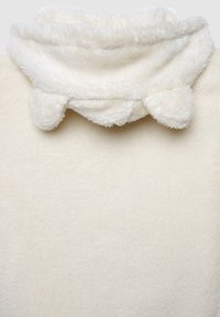 Kremowy, pluszowy materiał z wysokim kołnierzem z zaokrąglonymi akcentami. Miękka tekstura, ciepły wygląd, odpowiedni do codziennego noszenia.