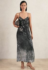 Schwarzes Maxikleid mit dünnen Trägern, das ein strukturiertes weißes Muster zeigt. Das Design integriert Grautöne und eine fließende Silhouette.