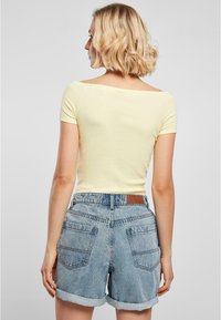 Gul, kortärmad topp med båthalsringning, kombinerad med ljusa denimshorts med uppvikt fåll och bakfickor, texturerad kvalitet.