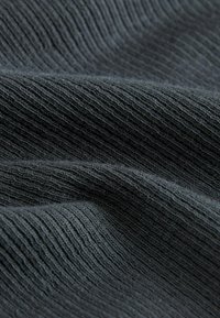 Tissu côtelé gris foncé avec une texture douce, présentant des plis et des rides qui mettent en valeur son élasticité et son motif de tissage.
