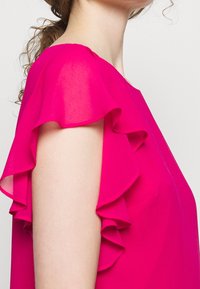 Fuchsia blouse featuring ruffled short sleeves, lightweight fabric, and a loose fit design. The neckline is round with a smooth finish.