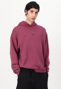 Felpa color prugna con cappuccio, tessuto morbido e vestibilità comoda. Presenta un piccolo logo sul petto; polsini e orlo sono a costine.